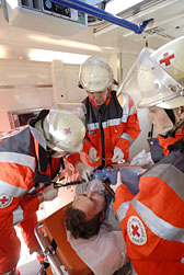 Foto: Drei DRK-Helfer versorgen einen verletzten Mann auf einer Trage in einem Einsatzfahrzeug.