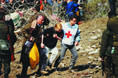 Foto: Ein Rotkreuzhelfer stützt Flüchtlinge, um durch die Grenzzone zu kommen - vorbei an bewaffneten Männern. Foto: Ein Rotkreuzhelfer stützt Flüchtlinge, um durch die Grenzzone zu kommen - vorbei an bewaffneten Männern.